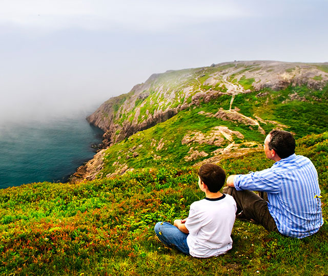 father and son sitting on hill